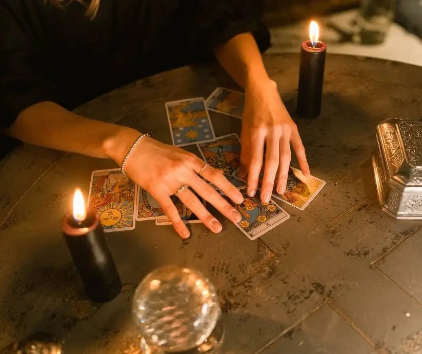 Hands holding tarot cards by candlelight